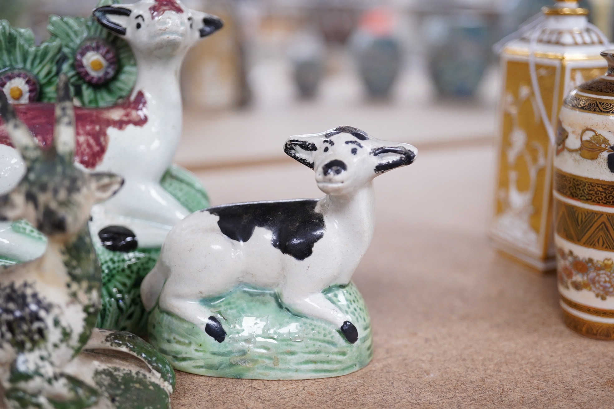 Two late 18th century Staffordshire coloured creamware figures of recumbent cows and a spongeware deer, largest 10cm wide (3). Condition - restored